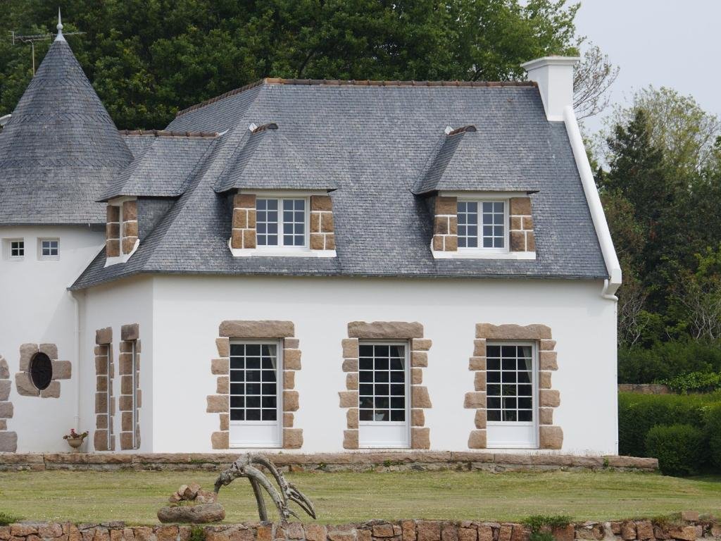 Maison traditionnelle bretonne avec murs blancs ravalés et toiture en ardoise